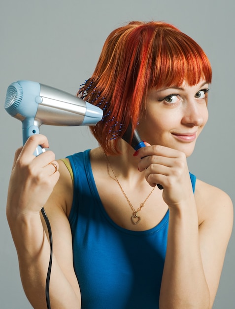 Mujer con secador de pelo y un cepillo para el cabello