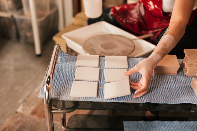 Mujer secando los pequeños azulejos blancos en taller.