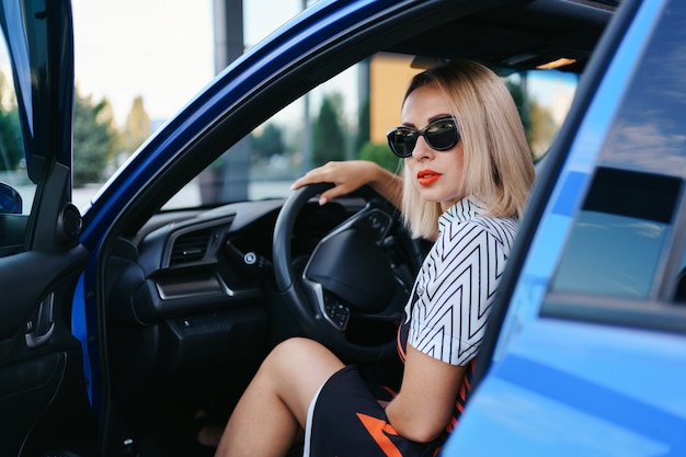 Mujer segura y hermosa en gafas de sol. Vista trasera de la atractiva mujer joven en ropa casual conduciendo un coche