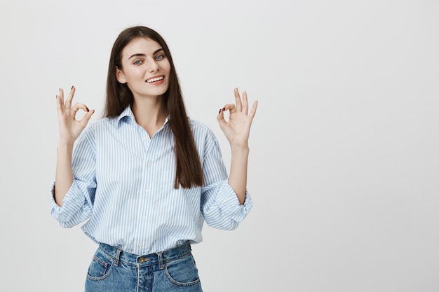 Mujer segura satisfecha sonriendo y mostrando gesto bien