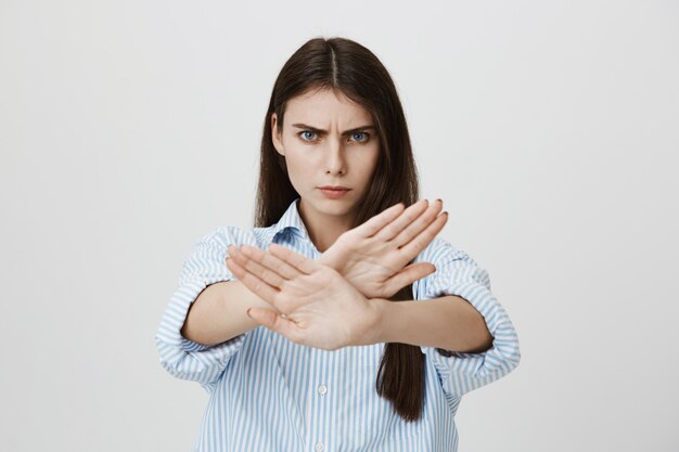 Mujer segura seria mostrar señal de stop, gesto cruzado