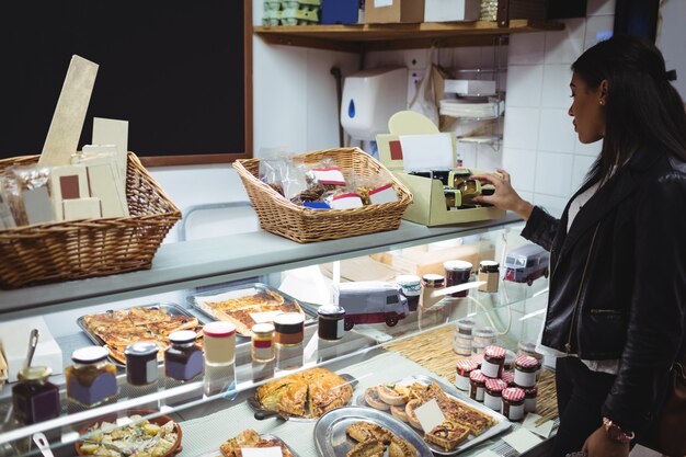 Mujer seleccionando alimentos envasados en el mostrador de alimentos