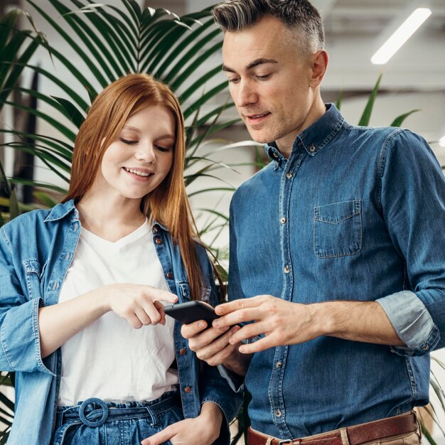 Mujer señalando algo en un teléfono a su compañero de trabajo