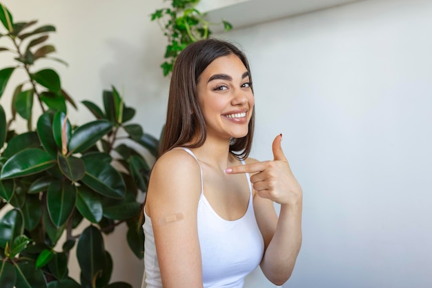 Mujer señalando su brazo con una venda después de recibir la vacuna covid19 mujer joven mostrando su hombro después de recibir la vacuna contra el coronavirus