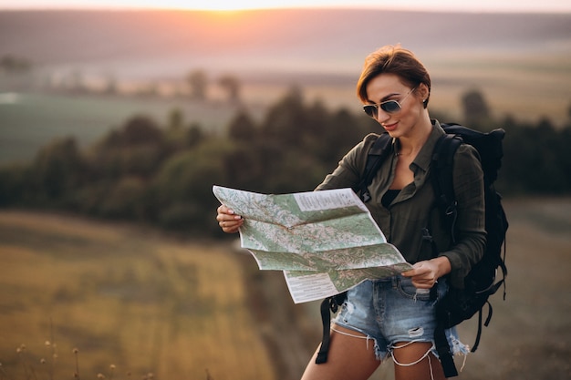 Mujer de senderismo en las montañas y mirando en el mapa