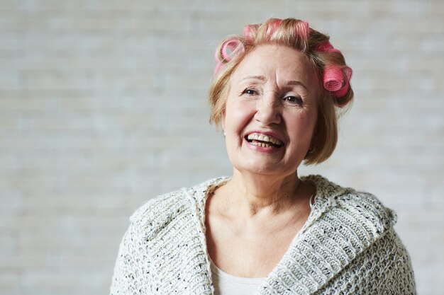 Foto gratuita mujer senior alegre con rizadores para el cabello