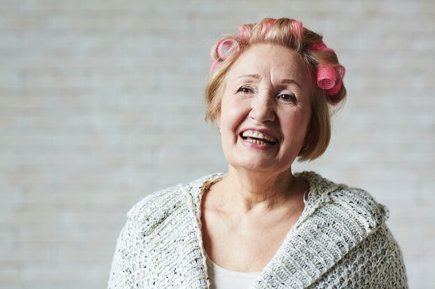 Mujer senior alegre con rizadores para el cabello