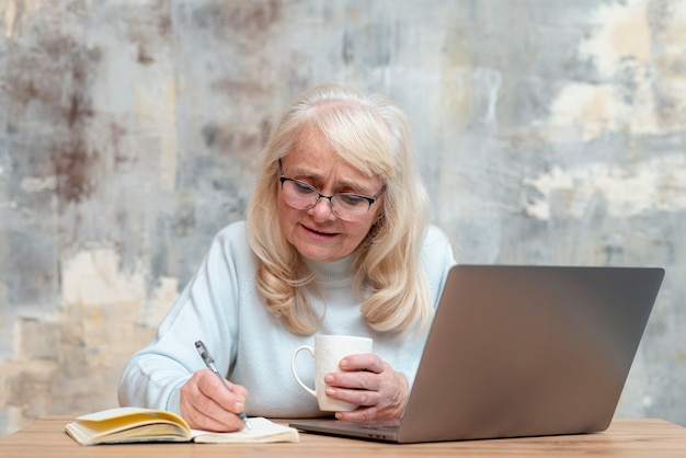 Foto gratuita mujer senior de alto ángulo tomando notas en agenda