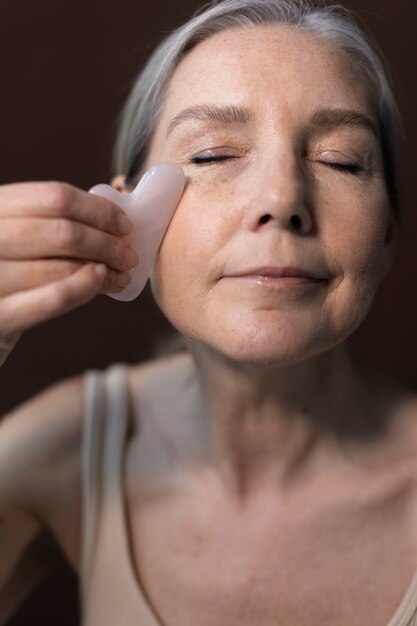 Mujer senior de alto ángulo usando gua sha