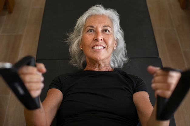 Foto gratuita mujer senior de ángulo alto en la clase de reformador de pilates