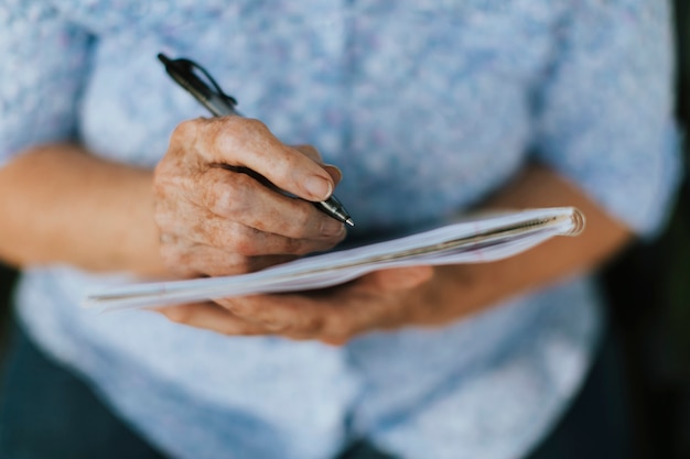 Mujer Senior anotando sus recuerdos en un cuaderno