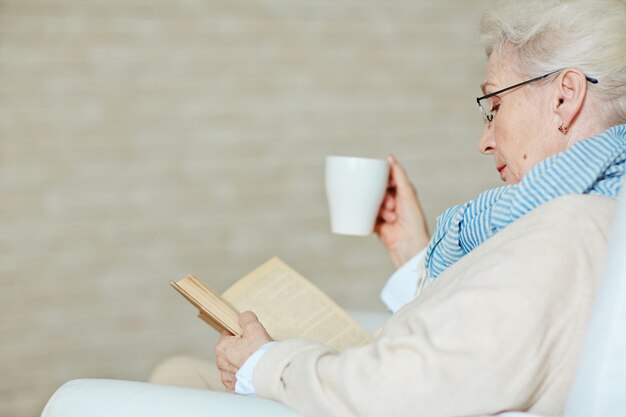 Mujer senior canosa con libro emocionante