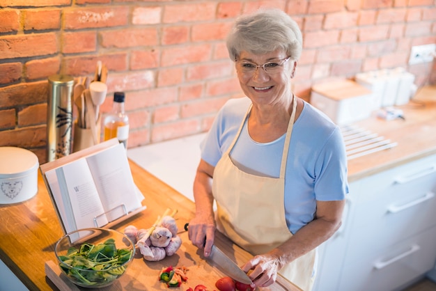 Mujer Senior cortando verduras de temporada