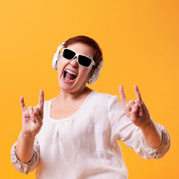 Mujer senior divertida escuchando música rock