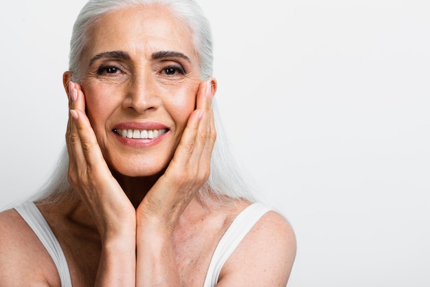 Mujer senior feliz aplicando crema para el cuidado de la piel