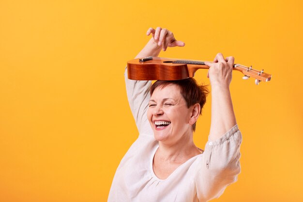 Foto gratuita mujer senior feliz tocando el ukelele