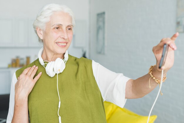 Mujer senior feliz viendo video en el teléfono móvil