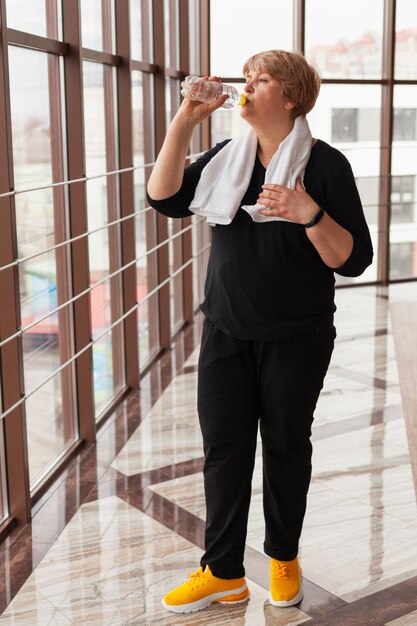 Foto gratuita mujer senior en el gimnasio hidratante