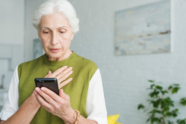 Mujer senior preocupada mirando smartphone