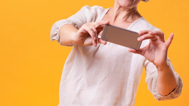 Foto gratuita mujer senior de primer plano con maqueta de teléfono