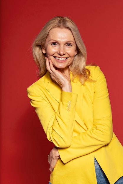 Foto gratuita mujer senior rubia posando y sonriendo contra un fondo rojo.