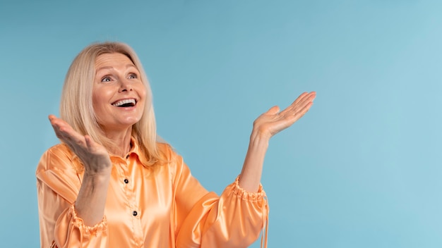 Mujer senior rubia siendo feliz contra un fondo azul.