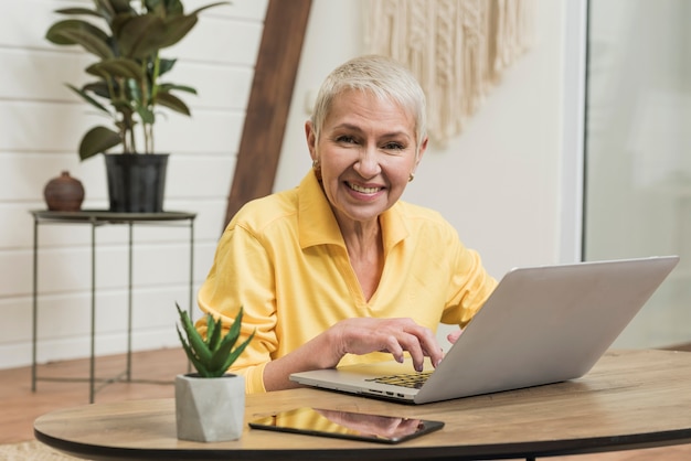 Foto gratuita mujer senior sonriente mirando en su computadora portátil