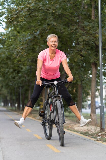 Mujer senior sonriente pasando un buen rato en bicicleta al aire libre