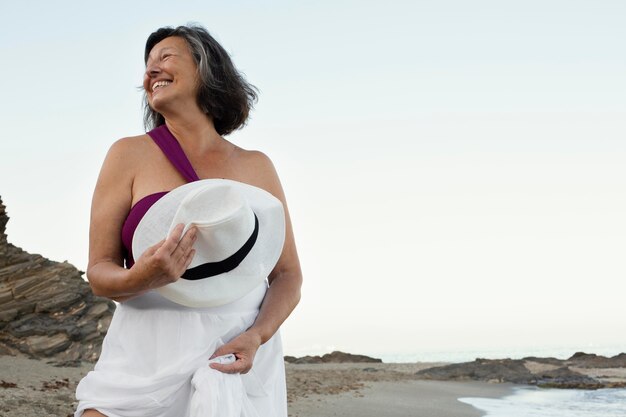 Mujer senior sonriente en la playa disfrutando de su día