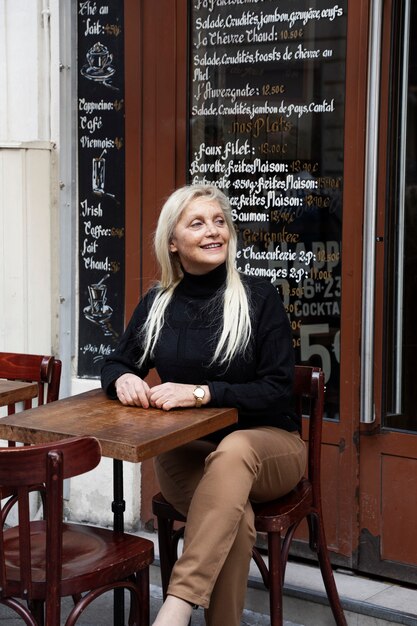 Mujer senior sonriente de tiro completo en bistro