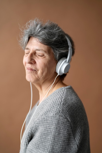 Foto gratuita mujer senior sonriente de tiro medio con auriculares