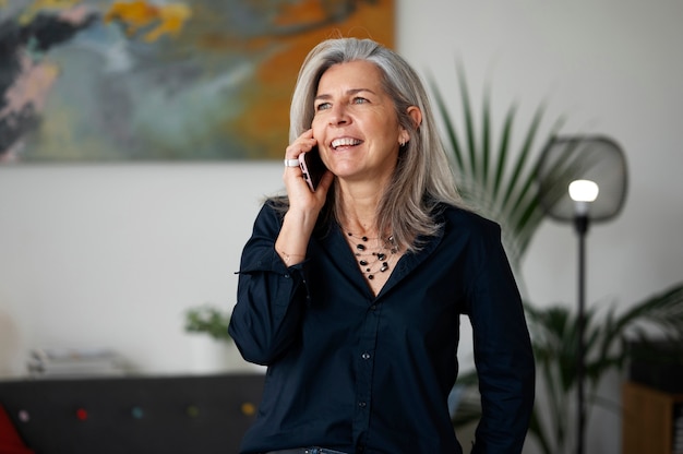 Mujer senior sonriente de tiro medio hablando por teléfono