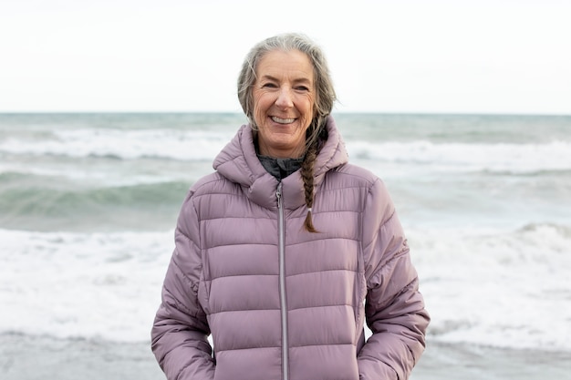 Mujer senior sonriente de tiro medio en la playa