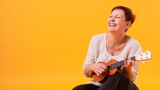 Mujer senior sonriente tocando la guitarra