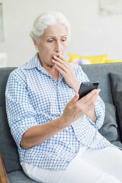 Mujer senior sorprendida mirando smartphone