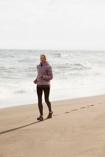 Foto gratuita mujer senior de tiro completo corriendo en la playa