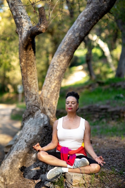 Mujer senior de tiro completo meditando en la naturaleza