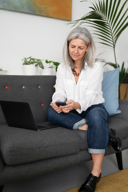 Foto gratuita mujer senior de tiro completo con teléfono inteligente