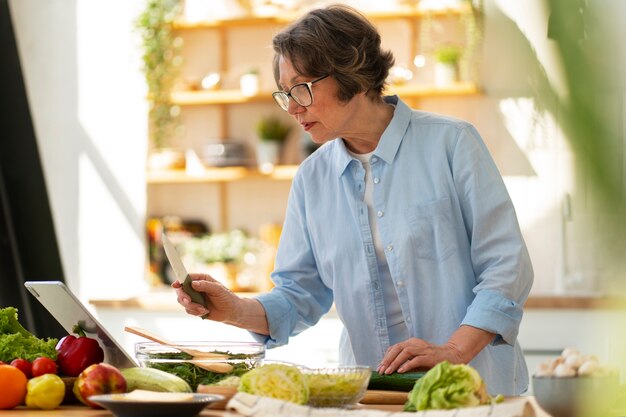 Mujer senior de tiro medio cocinando en la cocina