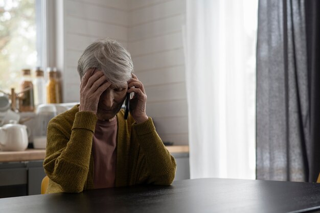 Mujer senior de tiro medio hablando por teléfono en casa