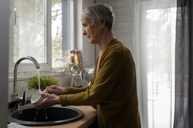 Foto gratuita mujer senior de tiro medio lavando platos