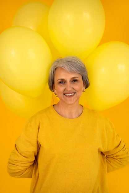 Mujer senior de tiro medio posando con globos