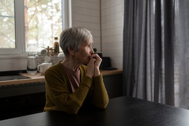 Foto gratuita mujer senior de tiro medio sentada en la mesa