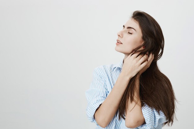 Mujer sensual y apasionada tocando el cabello, ojos cerrados de ensueño