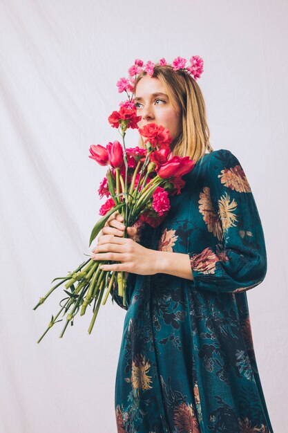 Mujer sensual atractiva con la guirnalda en la cabeza que huele el ramo de flores