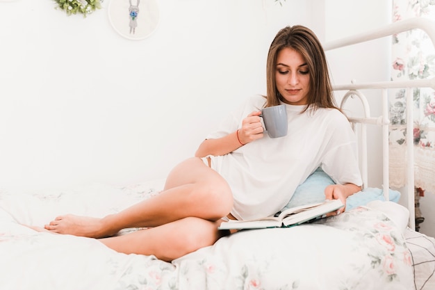 Mujer sensual bebiendo y leyendo el libro