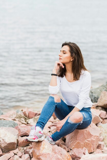 Mujer sentada al lado del mar