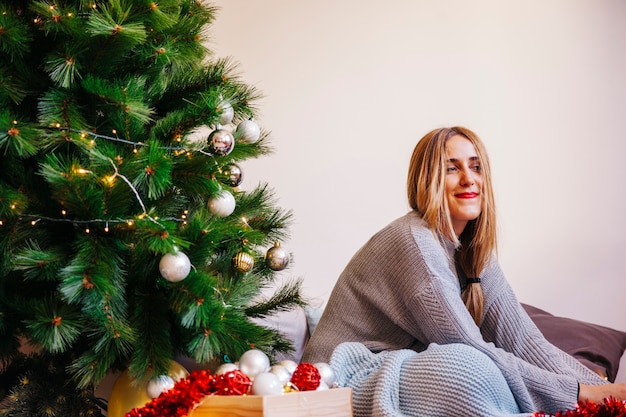 Mujer sentada al lado de su árbol de navidad