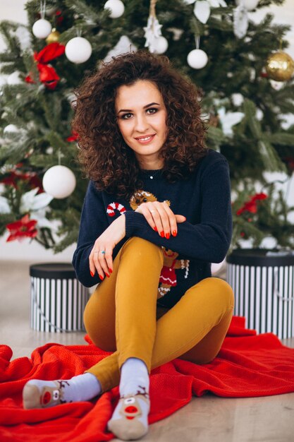 Mujer sentada por el árbol de navidad