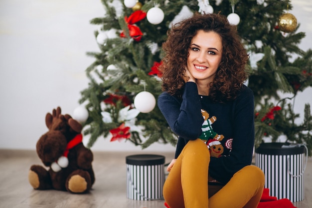 Mujer sentada por el árbol de navidad